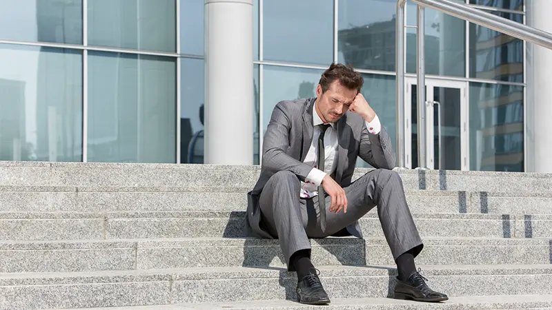 オフィスビル前の階段に座るビジネスマン