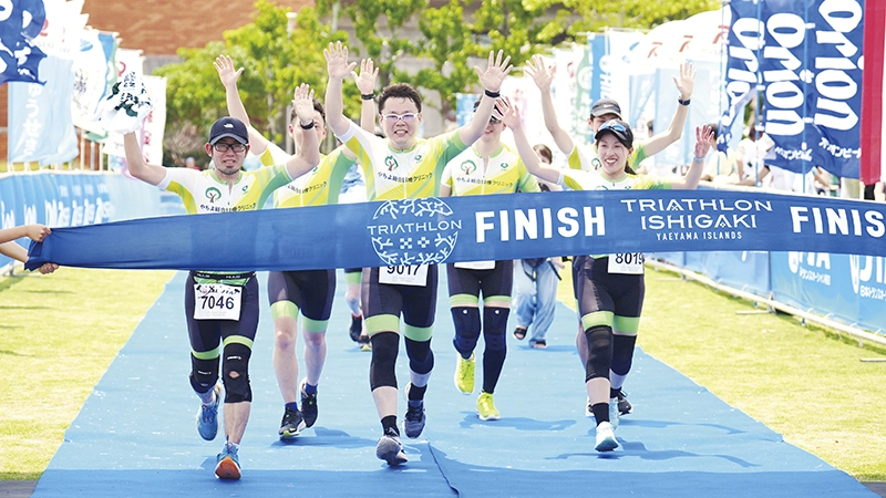 沖 一匡氏と梅澤慶太郎氏がトライアスロンの大会で万歳をしながらゴールをしているところ