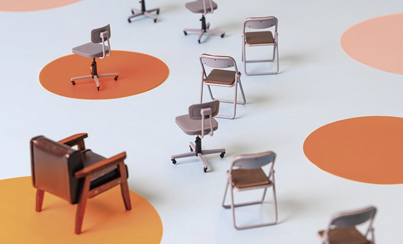円の上にバラバラに配置された、多様なデザインのミニチュア椅子の俯瞰写真。